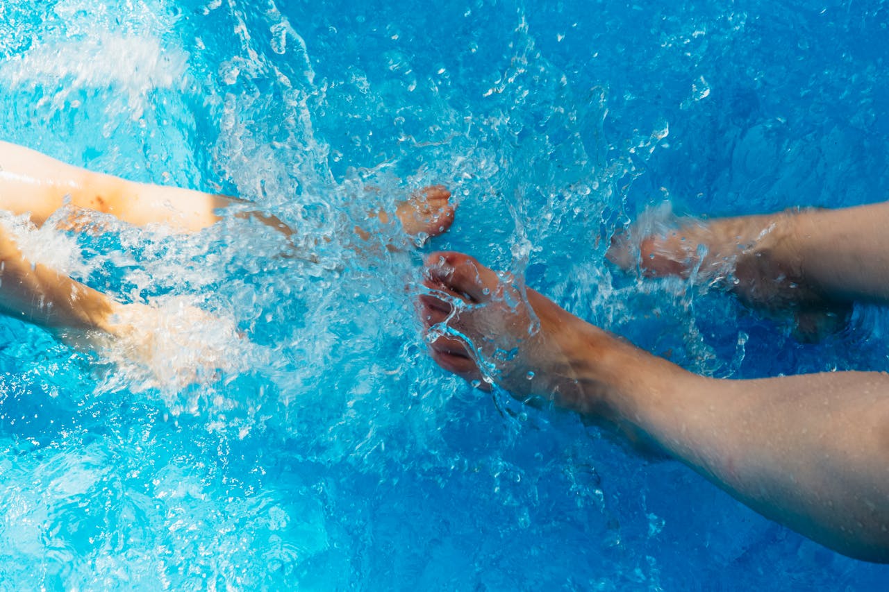 Two people playfully splashing water in a swimming pool. Perfect summer vibes.